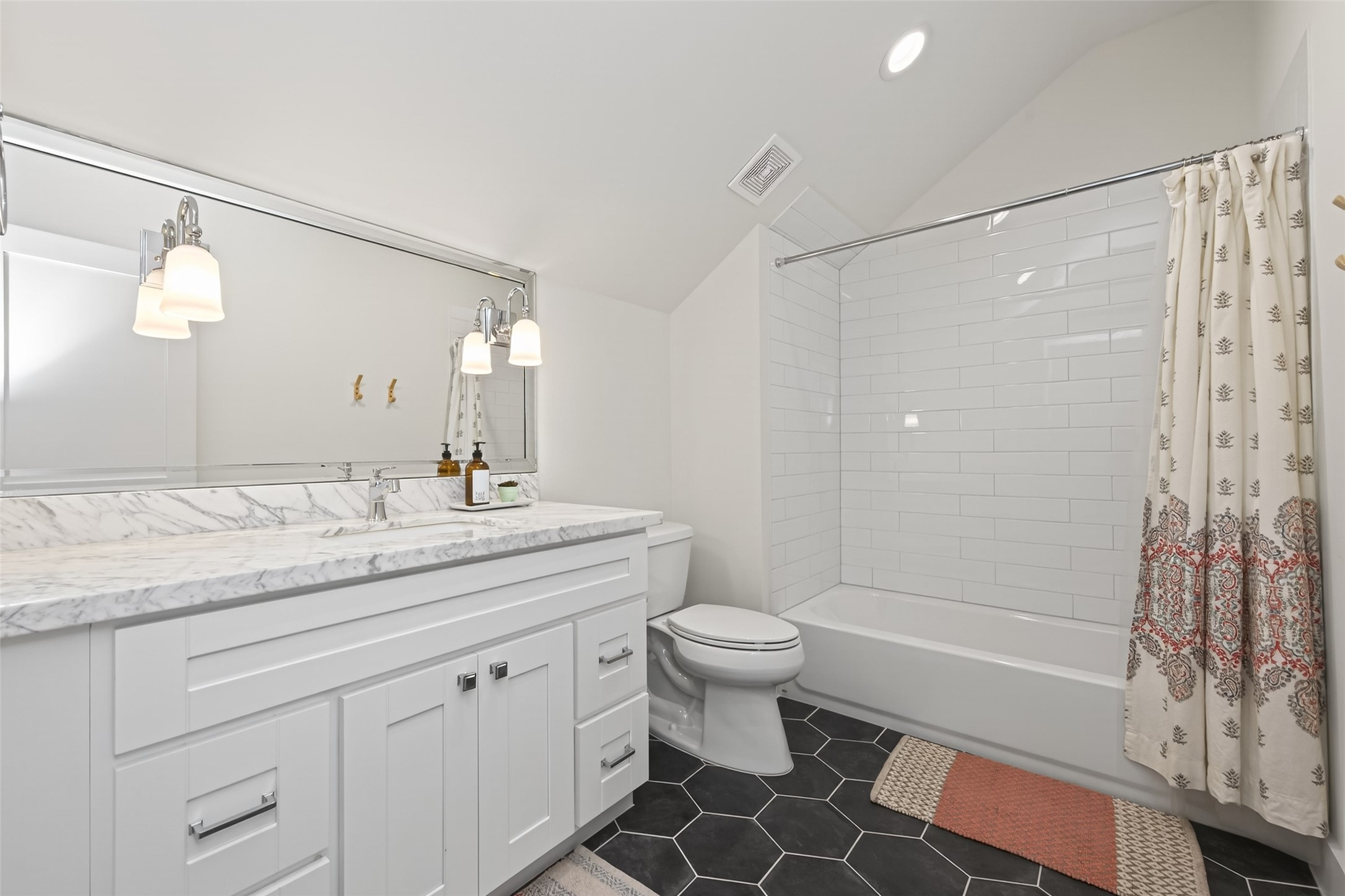 515 West 25th Street Houston, TX 77008 - Photo 25 of 35 10’3” x 6’6” third-floor bathroom features ceramic hex tile flooring, Carrara marble countertops, and a beveled mirror above a Shaker-style vanity with soft-close drawers, polished chrome pulls, square knobs, and coordinating hardware. The tub/shower combo, which includes a subway tile surround and polished chrome Signature Hardware tub and shower trim kit.