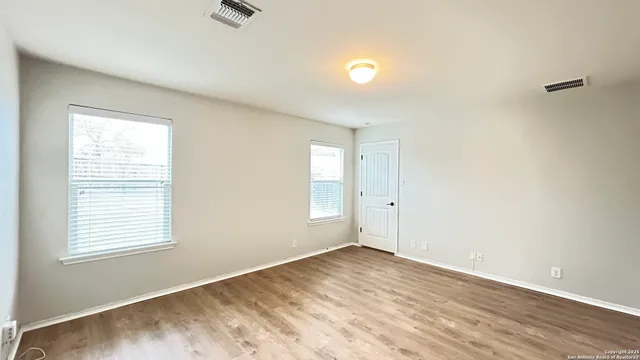 an empty room with wooden floor and windows