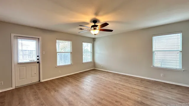 a view of an empty room with a window and a chandelier fan