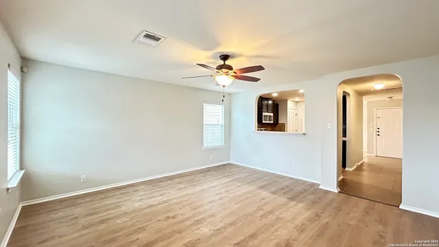 a view of an empty room with a ceiling fan and window