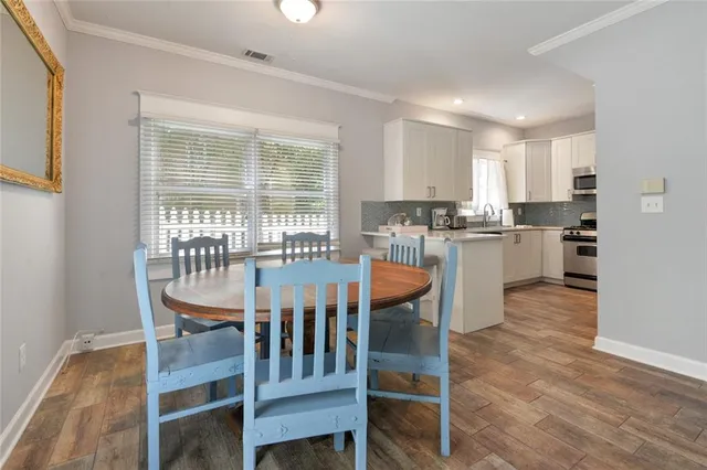 a dining room with stainless steel appliances kitchen island granite countertop a dining table chairs and granite counter tops
