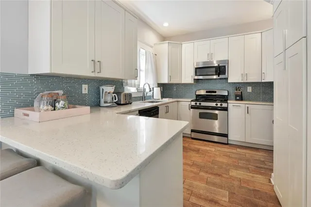 a kitchen with stainless steel appliances a stove a sink a refrigerator white cabinets and a refrigerator