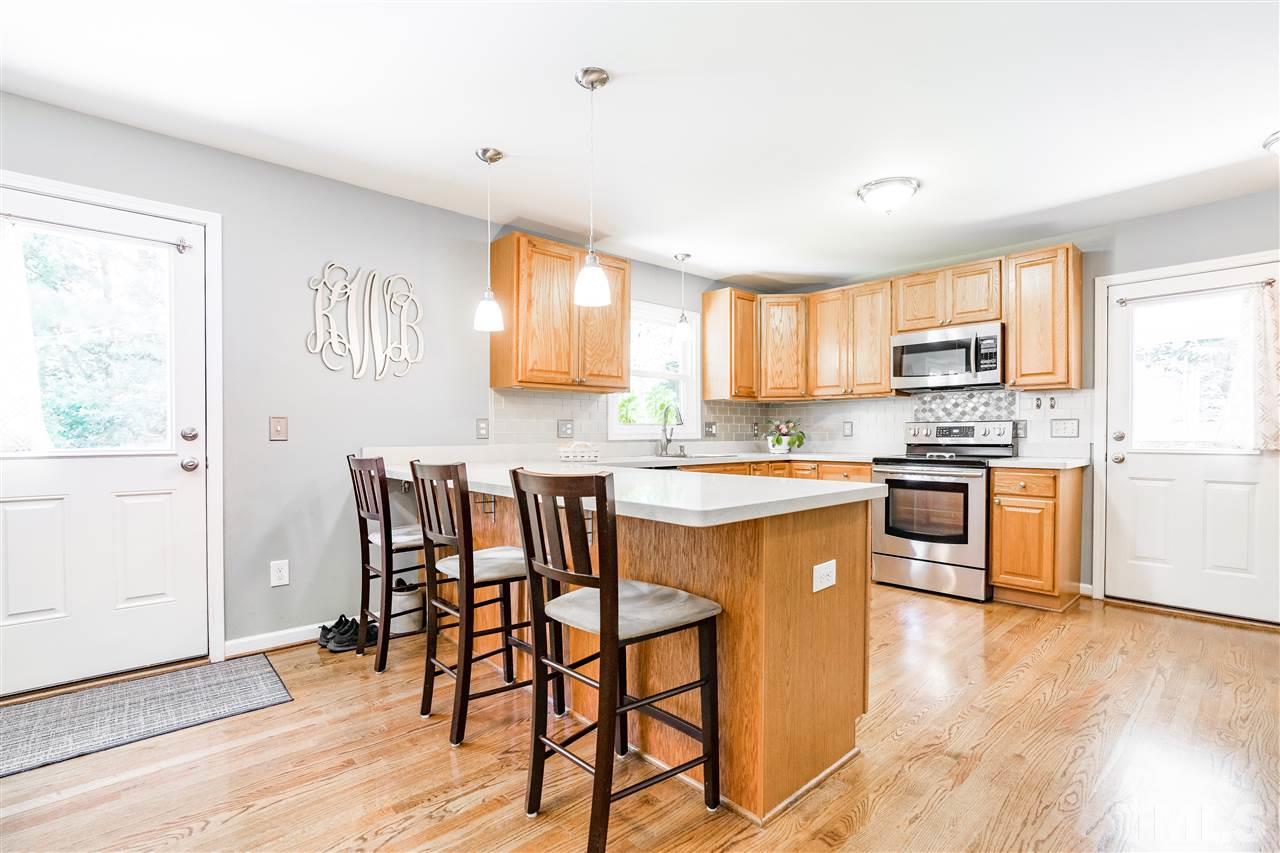 1005 Plateau Lane Raleigh, NC 27615 - Photo 8 of 29 a kitchen with stainless steel appliances granite countertop a stove top oven a sink a dining table and chairs with wooden floor
