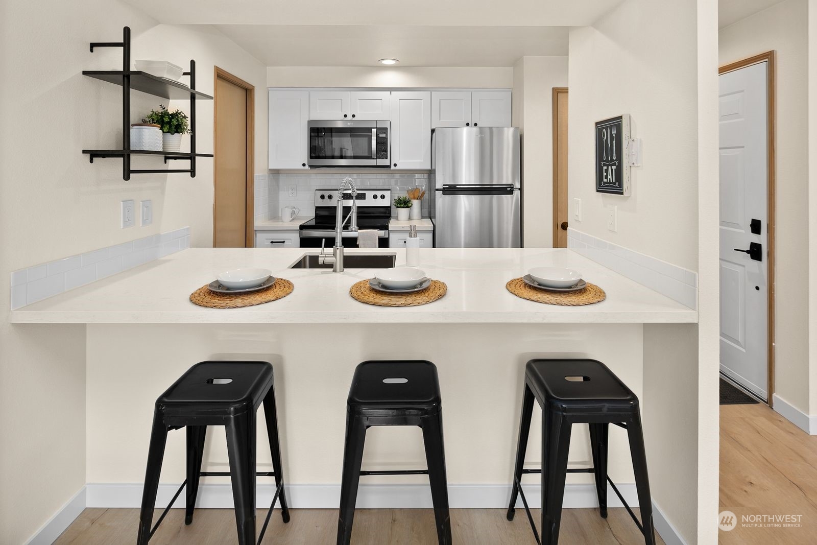 5421 Fauntleroy Way Southwest, Unit A Seattle, WA 98136 - Photo 7 of 18 a kitchen with stainless steel appliances kitchen island granite countertop a dining table and chairs with wooden floor