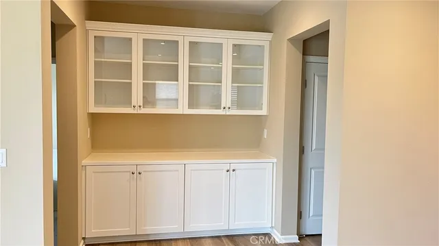 a view of an empty room with wooden floor and cabinets