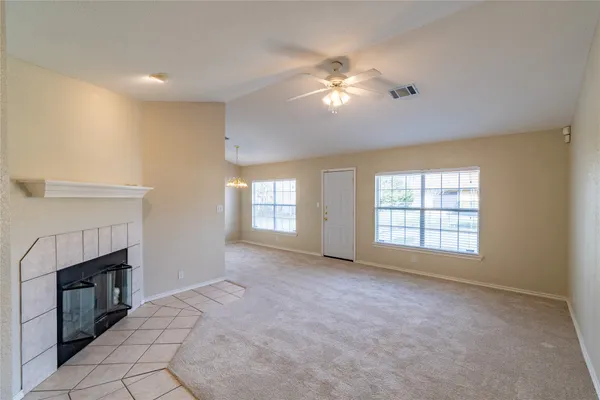 a view of an empty room with chandelier fan and fire place
