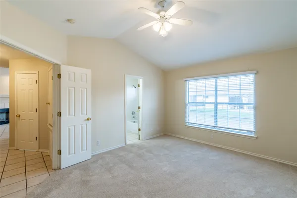 an empty room with chandelier fan and windows