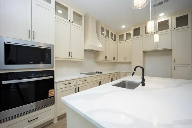 a kitchen with stainless steel appliances granite countertop a sink and a stove top oven with white cabinets