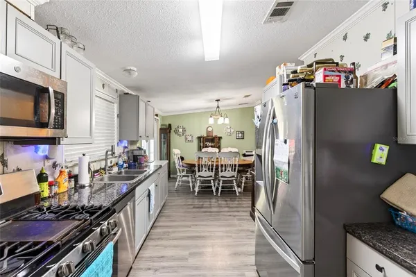 a kitchen with stainless steel appliances granite countertop a refrigerator and a dining table