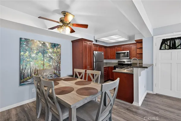 a kitchen with stainless steel appliances granite countertop a refrigerator a stove and a sink with wooden floor