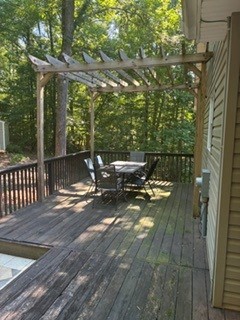 203 Indian Trail Road Seneca, SC 29672 - Photo 14 of 14 An inviting wooden deck features a shady pergola overlooking a serene wooded backdrop.