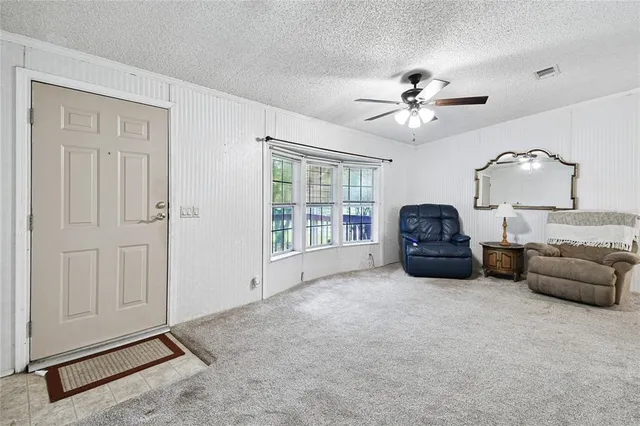 an empty room with windows and fan