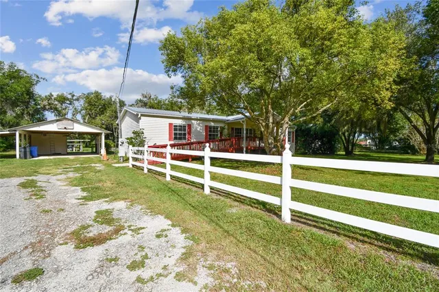 a view of a house with a big yard plants and large trees