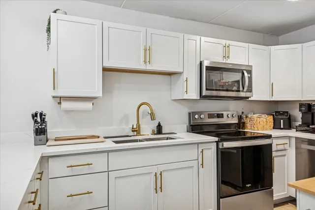 a kitchen with granite countertop white cabinets stainless steel appliances and a sink