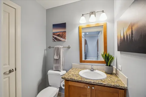 a bathroom with a granite countertop sink and a mirror with toilet