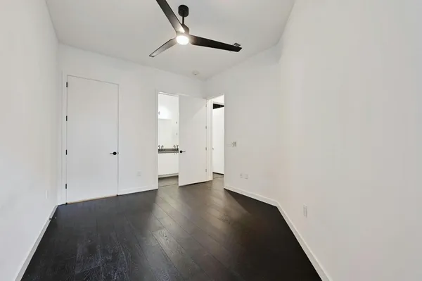 an empty room with wooden floor and ceiling fan