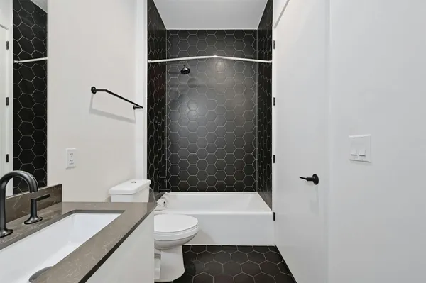 a bathroom with a granite countertop bathtub shower sink vanity and toilet