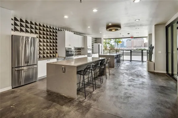 a kitchen with stainless steel appliances kitchen island granite countertop a refrigerator a stove a sink a dining table and chairs