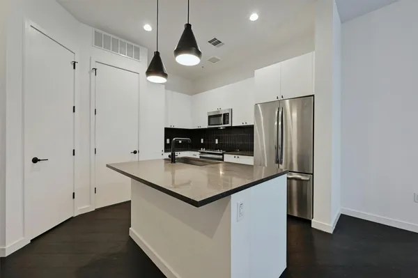 a kitchen with stainless steel appliances granite countertop a refrigerator a sink and a stove