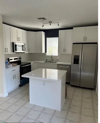 a kitchen with stainless steel appliances granite countertop a stove a sink a microwave a refrigerator and cabinets