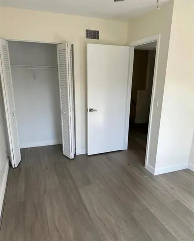 an empty room with wooden floor and closet