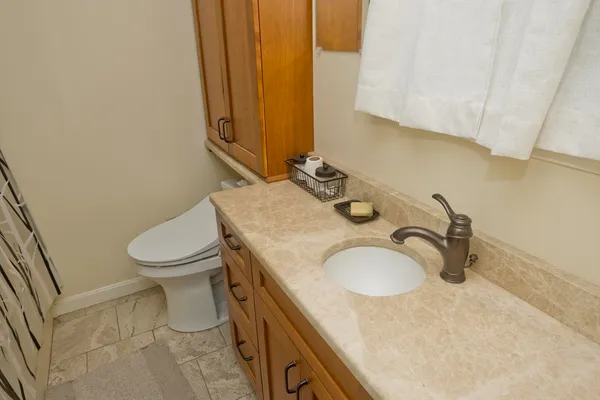a bathroom with a granite countertop sink and a toilet