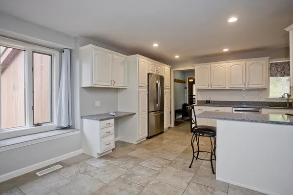 a kitchen with granite countertop a refrigerator stove top oven and sink