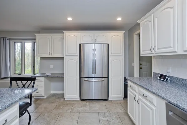 a kitchen with granite countertop a refrigerator and wooden cabinets