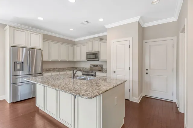 a kitchen with stainless steel appliances granite countertop a refrigerator a stove and a sink