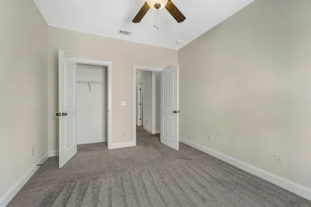 an empty room with ceiling fan and window