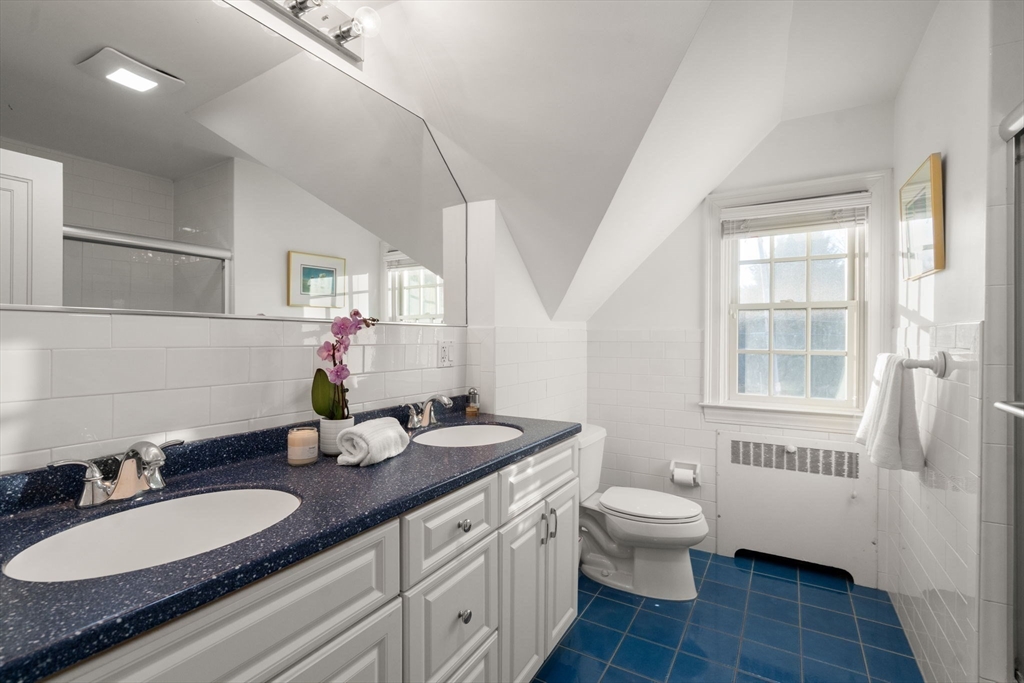 55 Evelyn Road Newton, MA 02468 - Photo 20 of 30 a bathroom with a granite countertop double vanity sinks a mirror a toilet a vanity and a window