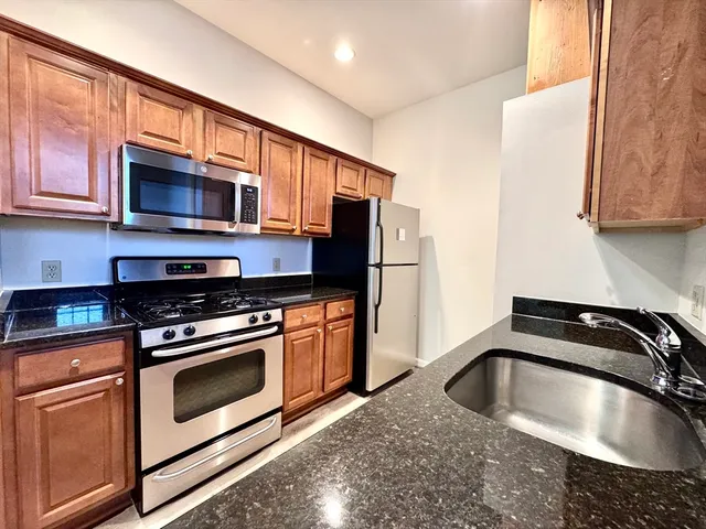 a kitchen with stainless steel appliances granite countertop a sink stove and refrigerator