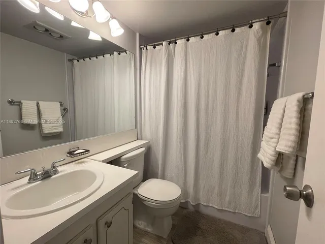 a bathroom with a sink a toilet and shower curtain