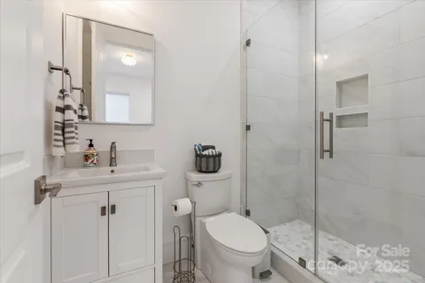 a bathroom with a toilet sink vanity granite and shower