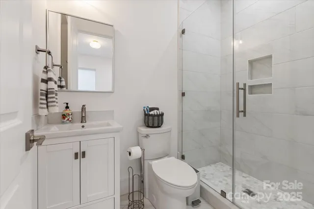 a bathroom with a toilet sink vanity granite and shower