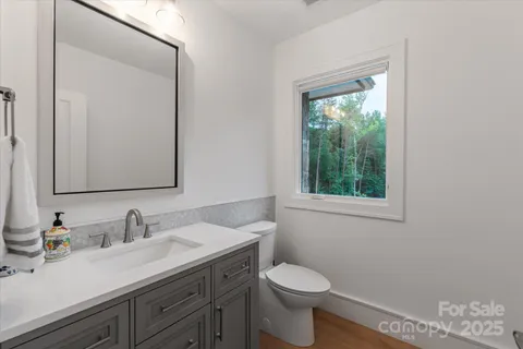 a bathroom with a granite countertop sink vanity mirror and toilet