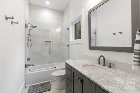 a bathroom with a granite countertop sink a toilet and shower