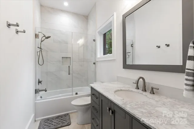 a bathroom with a granite countertop sink a toilet and shower