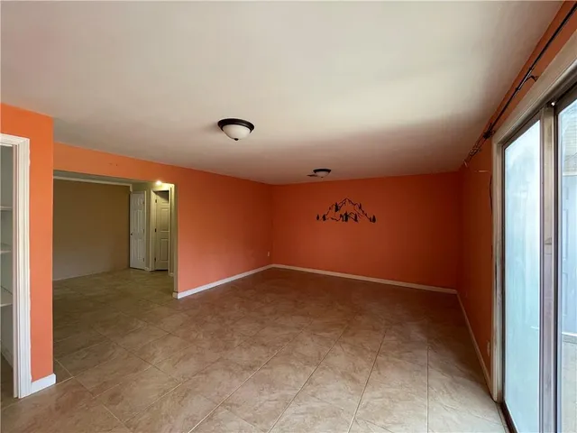 an empty room with wooden floor mirror and windows