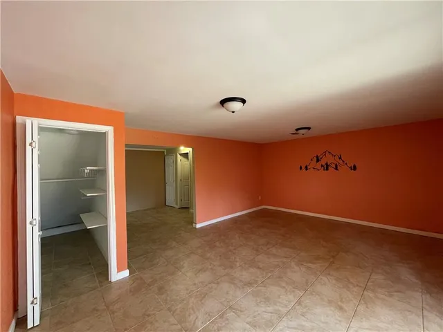 an empty room with wooden floor fireplace and windows