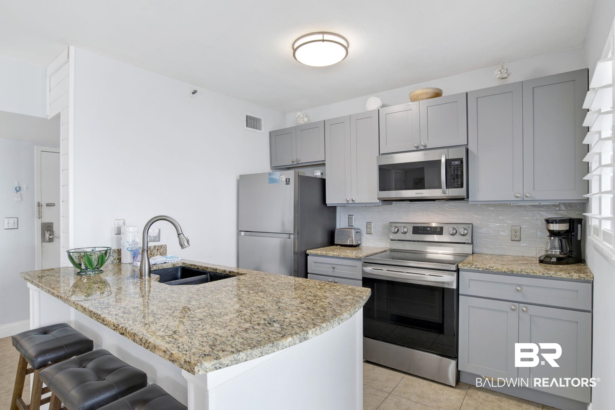 375 Plantation Road, Unit 5514 Gulf Shores, AL 36542 - Photo 16 of 44 Kitchen with appliances with stainless steel finishes, gray cabinetry, backsplash, and light stone countertops
