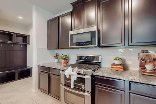 a kitchen with stainless steel appliances granite countertop a kitchen island a refrigerator a sink a stove a dining table and chairs