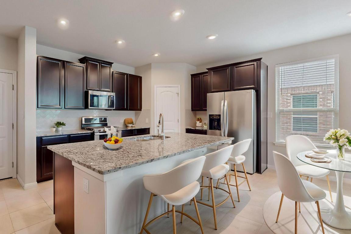 2908 Harvester Lane Round Rock, TX 78664 - Photo 38 of 40 a kitchen with stainless steel appliances granite countertop a kitchen island a refrigerator a sink a stove a dining table and chairs