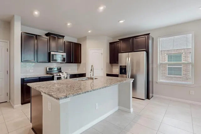 a kitchen with stainless steel appliances granite countertop a refrigerator a sink a stove a microwave and island