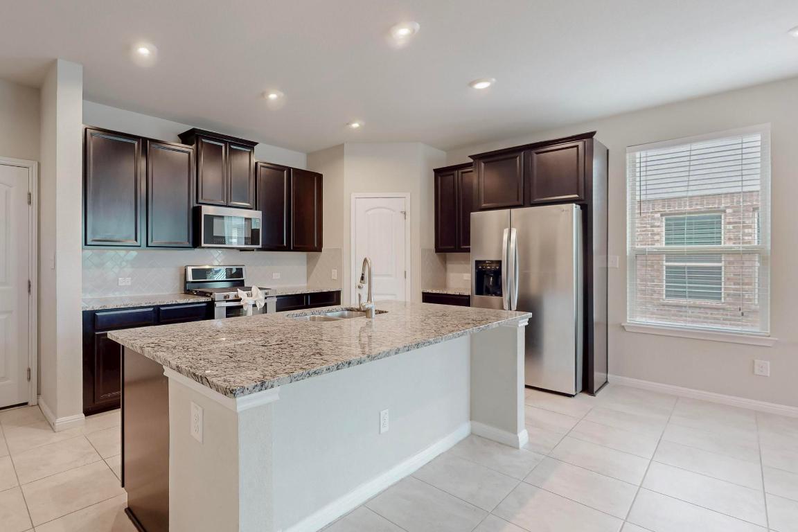 2908 Harvester Lane Round Rock, TX 78664 - Photo 9 of 40 a kitchen with stainless steel appliances granite countertop a refrigerator a sink a stove a microwave and island