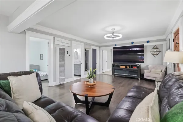 a living room with furniture a flat screen tv and a dining table with wooden floor