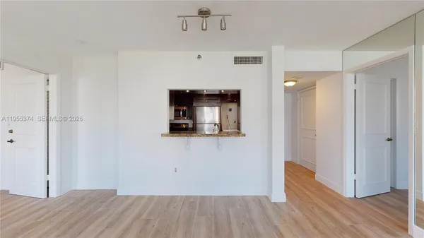 a view of a hallway with wooden floor and a bathroom