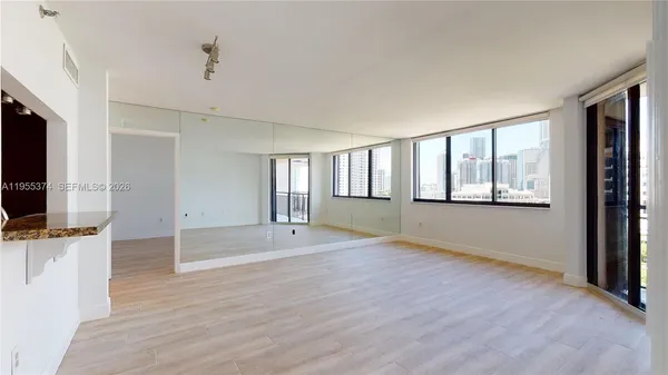 a view of an empty room with a window and wooden floor