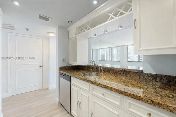 a kitchen with granite countertop a sink and white cabinets