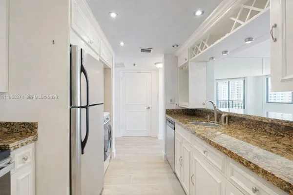 a kitchen with granite countertop a refrigerator and a sink